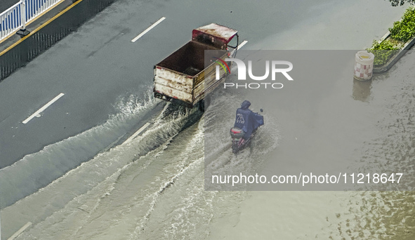 Cars are wading through a flooded road amid an orange rainstorm alert in Nanning, Guangxi Province, China, on May 8, 2024. 