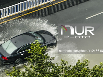 Cars are wading through a flooded road amid an orange rainstorm alert in Nanning, Guangxi Province, China, on May 8, 2024. (