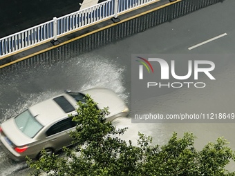 Cars are wading through a flooded road amid an orange rainstorm alert in Nanning, Guangxi Province, China, on May 8, 2024. (