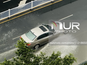 Cars are wading through a flooded road amid an orange rainstorm alert in Nanning, Guangxi Province, China, on May 8, 2024. (