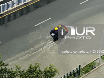 Cars are wading through a flooded road amid an orange rainstorm alert in Nanning, Guangxi Province, China, on May 8, 2024. (