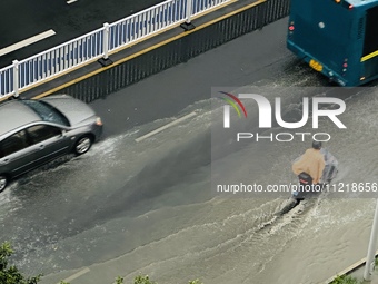 Cars are wading through a flooded road amid an orange rainstorm alert in Nanning, Guangxi Province, China, on May 8, 2024. (