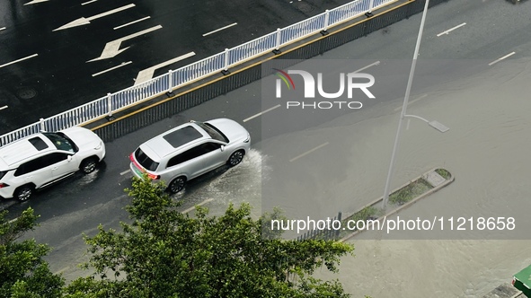 Cars are wading through a flooded road amid an orange rainstorm alert in Nanning, Guangxi Province, China, on May 8, 2024. 