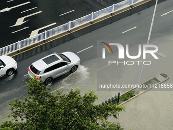 Cars are wading through a flooded road amid an orange rainstorm alert in Nanning, Guangxi Province, China, on May 8, 2024. (