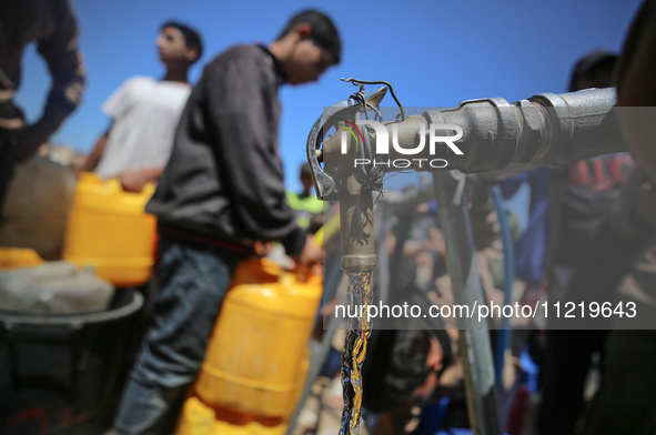 Displaced Palestinians are filling jerrycans with water at a desalination plant in Deir el-Balah in the central Gaza Strip, on May 8, 2024,...