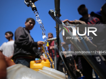 Displaced Palestinians are filling jerrycans with water at a desalination plant in Deir el-Balah in the central Gaza Strip, on May 8, 2024,...