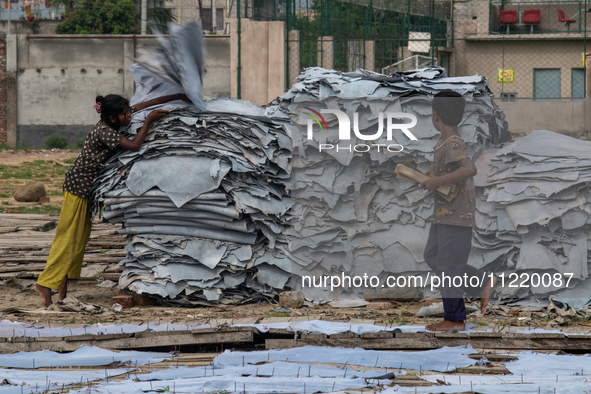 A child is carrying leather pieces to dry them at a tannery in a low-income area in Dhaka, Bangladesh, on May 8, 2024. Despite the labor law...