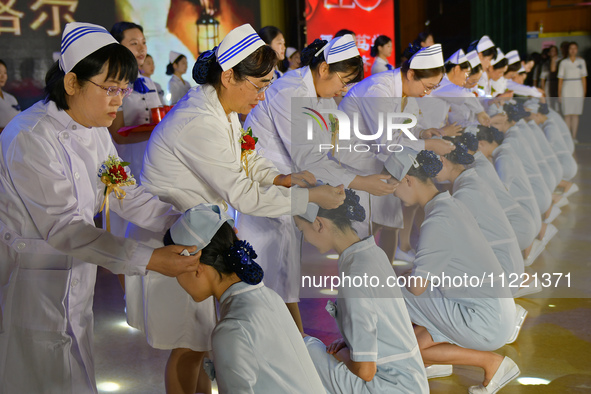 Senior nurses are giving hats to students during a hat-awarding ceremony at a nursing school in Yantai, Shandong Province, China, on May 8,...