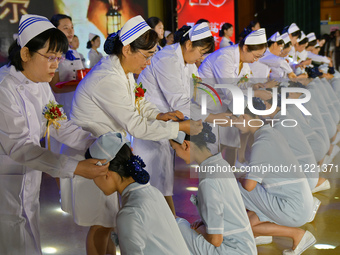 Senior nurses are giving hats to students during a hat-awarding ceremony at a nursing school in Yantai, Shandong Province, China, on May 8,...