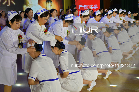 Senior nurses are giving hats to students during a hat-awarding ceremony at a nursing school in Yantai, Shandong Province, China, on May 8,...