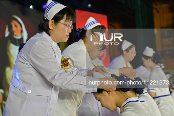 Senior nurses are giving hats to students during a hat-awarding ceremony at a nursing school in Yantai, Shandong Province, China, on May 8,...