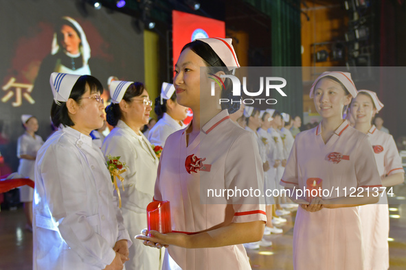 Students are holding red candles, a symbol of dedication, during a hat-giving ceremony at a nursing school in Yantai, Shandong Province, Chi...