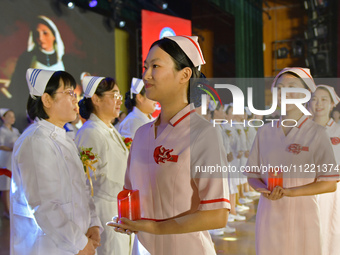 Students are holding red candles, a symbol of dedication, during a hat-giving ceremony at a nursing school in Yantai, Shandong Province, Chi...