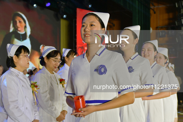 Students are holding red candles, a symbol of dedication, during a hat-giving ceremony at a nursing school in Yantai, Shandong Province, Chi...