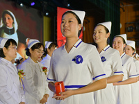 Students are holding red candles, a symbol of dedication, during a hat-giving ceremony at a nursing school in Yantai, Shandong Province, Chi...