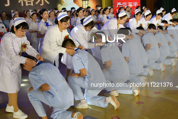 Senior nurses are giving ribbons to students during a hat-awarding ceremony at a nursing school in Yantai, Shandong Province, China, on May...