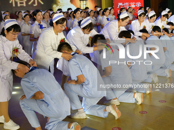 Senior nurses are giving ribbons to students during a hat-awarding ceremony at a nursing school in Yantai, Shandong Province, China, on May...