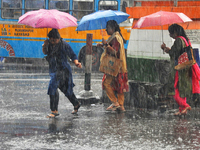 Women are holding umbrellas as they walk in the monsoon rain in Kolkata, India, on May 9, 2024. (