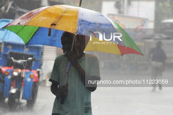 A man is holding umbrellas as he walks in the monsoon rain in Kolkata, India, on May 9, 2024. 