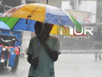 A man is holding umbrellas as he walks in the monsoon rain in Kolkata, India, on May 9, 2024. (