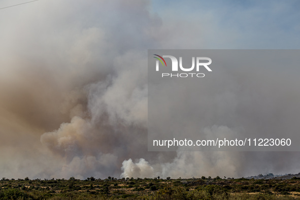 Smoke is rising behind the hill in Limassol, Cyprus, on May 9, 2024. A wildfire has broken out at the Industrial Zone of Ipsonas, a few kilo...