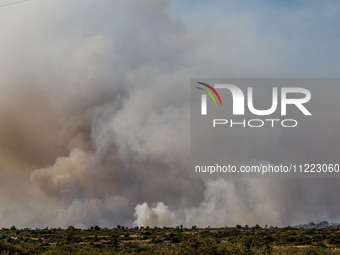 Smoke is rising behind the hill in Limassol, Cyprus, on May 9, 2024. A wildfire has broken out at the Industrial Zone of Ipsonas, a few kilo...