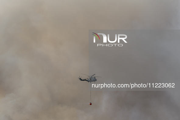 A helicopter is being seen through the thick smoke in Limassol, Cyprus, on May 9, 2024. A wildfire is breaking out at the Industrial Zone of...