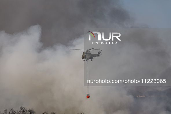 A helicopter is being seen through the thick smoke in Limassol, Cyprus, on May 9, 2024. A wildfire is breaking out at the Industrial Zone of...