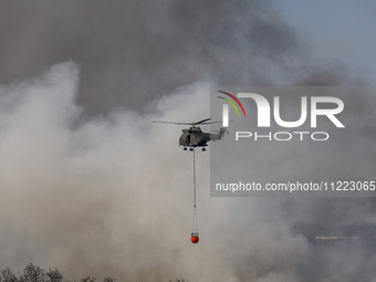 A helicopter is being seen through the thick smoke in Limassol, Cyprus, on May 9, 2024. A wildfire is breaking out at the Industrial Zone of...