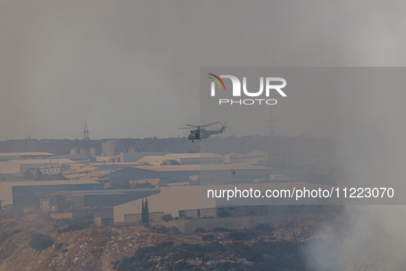 A helicopter is flying over industrial sites in Limassol, Cyprus, on May 9, 2024. A wildfire has broken out at the Industrial Zone of Ipsona...