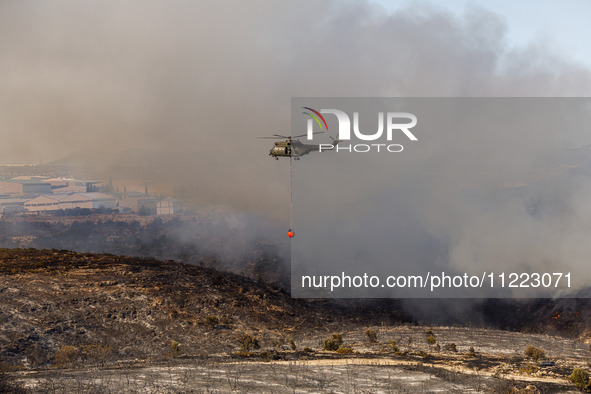 A helicopter is operating during a fire in Limassol, Cyprus, on May 9, 2024. The wildfire, which broke out in the Industrial Zone of Ipsonas...