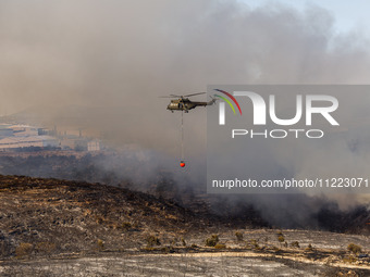 A helicopter is operating during a fire in Limassol, Cyprus, on May 9, 2024. The wildfire, which broke out in the Industrial Zone of Ipsonas...