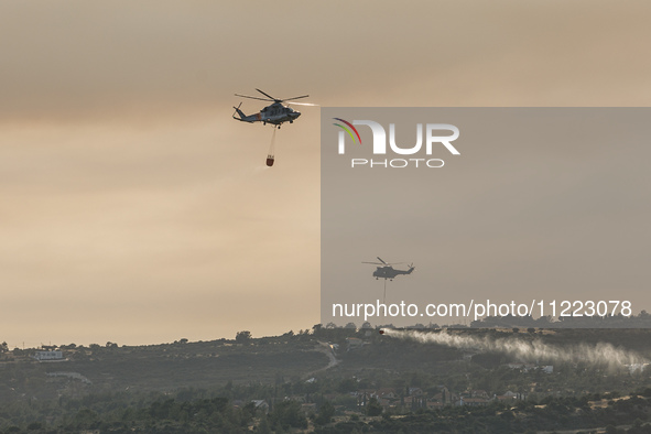 Helicopters are flying over the area during a fire in Limassol, Cyprus, on May 9, 2024. The wildfire, which started in the Industrial Zone o...