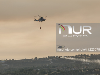 Helicopters are flying over the area during a fire in Limassol, Cyprus, on May 9, 2024. The wildfire, which started in the Industrial Zone o...