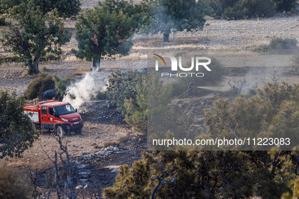 A fireman is putting out a small fire in Limassol, Cyprus, on May 9, 2024. The wildfire, which broke out in the Industrial Zone of Ipsonas a...