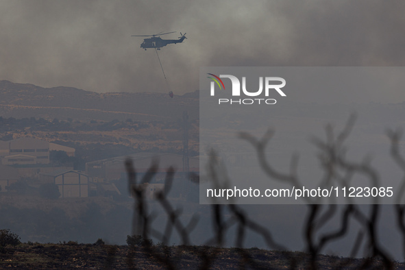 A helicopter is operating during a fire in Limassol, Cyprus, on May 9, 2024. The wildfire, which broke out in the Industrial Zone of Ipsonas...