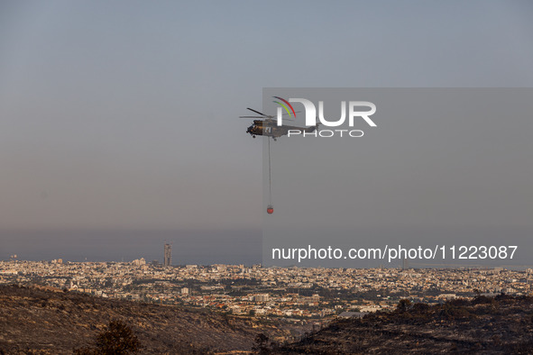 A helicopter is operating during the fire with the city in the background in Limassol, Cyprus, on May 9, 2024. The wildfire, which broke out...