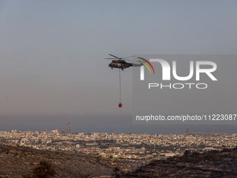 A helicopter is operating during the fire with the city in the background in Limassol, Cyprus, on May 9, 2024. The wildfire, which broke out...