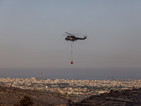 A helicopter is operating during the fire with the city in the background in Limassol, Cyprus, on May 9, 2024. The wildfire, which broke out...