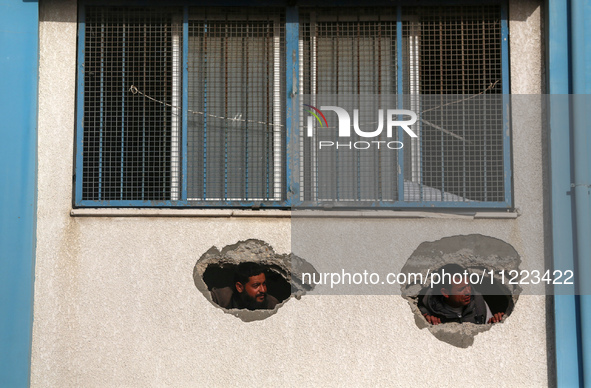 Displaced Palestinians are looking through a hole in the wall of a school after returning to Khan Yunis in the southern Gaza Strip amid the...