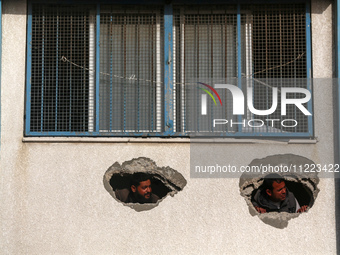 Displaced Palestinians are looking through a hole in the wall of a school after returning to Khan Yunis in the southern Gaza Strip amid the...