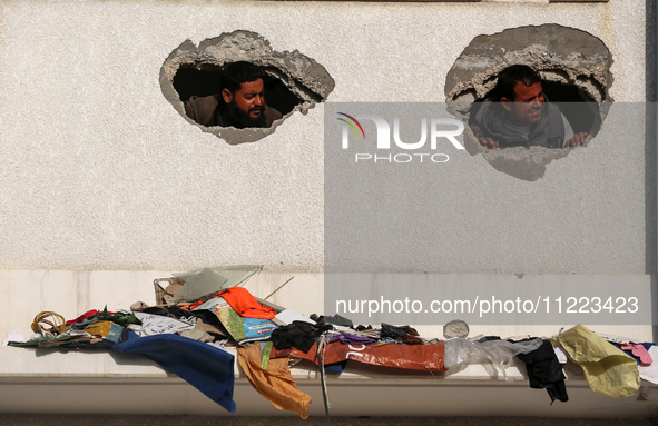 Displaced Palestinians are looking through a hole in the wall of a school after returning to Khan Yunis in the southern Gaza Strip amid the...