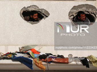 Displaced Palestinians are looking through a hole in the wall of a school after returning to Khan Yunis in the southern Gaza Strip amid the...