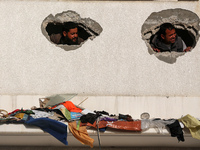 Displaced Palestinians are looking through a hole in the wall of a school after returning to Khan Yunis in the southern Gaza Strip amid the...