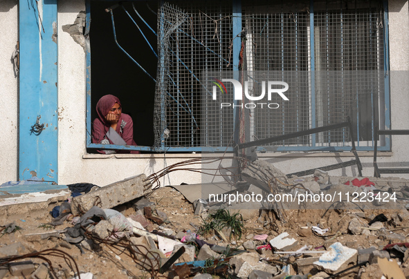 A displaced Palestinian woman is looking out of a school window after returning to Khan Yunis in the southern Gaza Strip, on May 9, 2024, am...