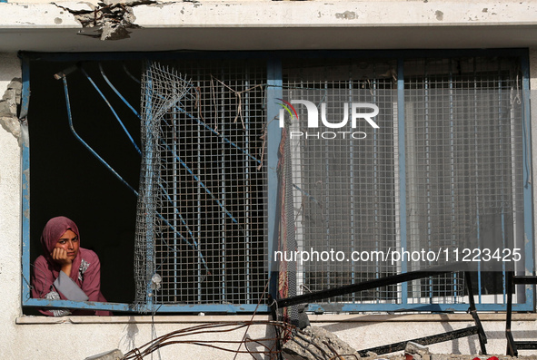 A displaced Palestinian woman is looking out of a school window after returning to Khan Yunis in the southern Gaza Strip, on May 9, 2024, am...