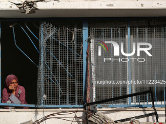 A displaced Palestinian woman is looking out of a school window after returning to Khan Yunis in the southern Gaza Strip, on May 9, 2024, am...