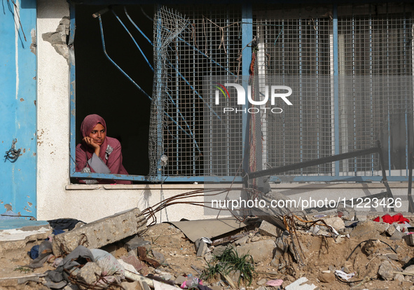 A displaced Palestinian woman is looking out of a school window after returning to Khan Yunis in the southern Gaza Strip, on May 9, 2024, am...