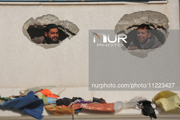 Displaced Palestinians are looking through a hole in the wall of a school after returning to Khan Yunis in the southern Gaza Strip amid the...