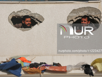 Displaced Palestinians are looking through a hole in the wall of a school after returning to Khan Yunis in the southern Gaza Strip amid the...